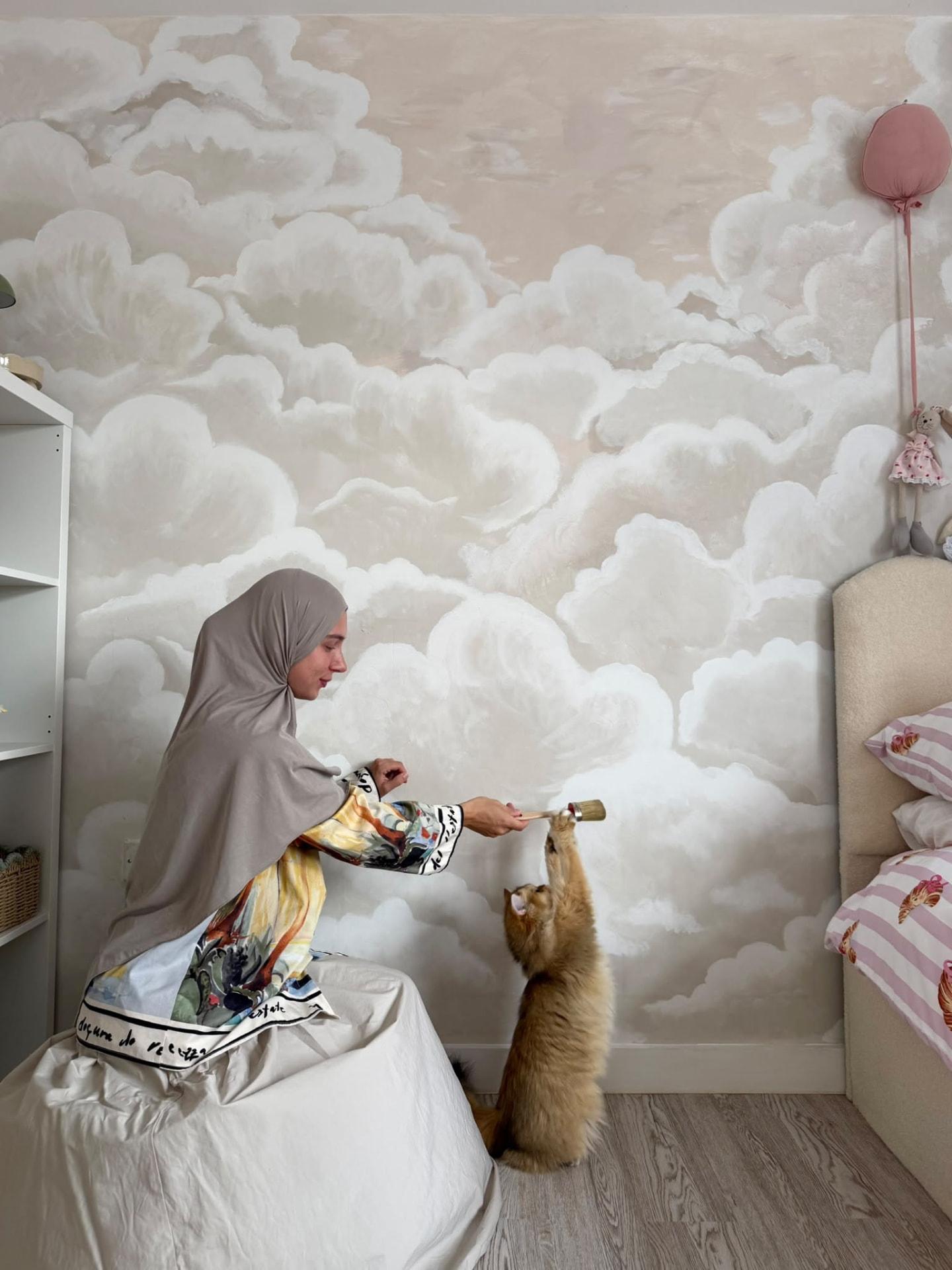 Charlie working on a cloud mural in a children's room