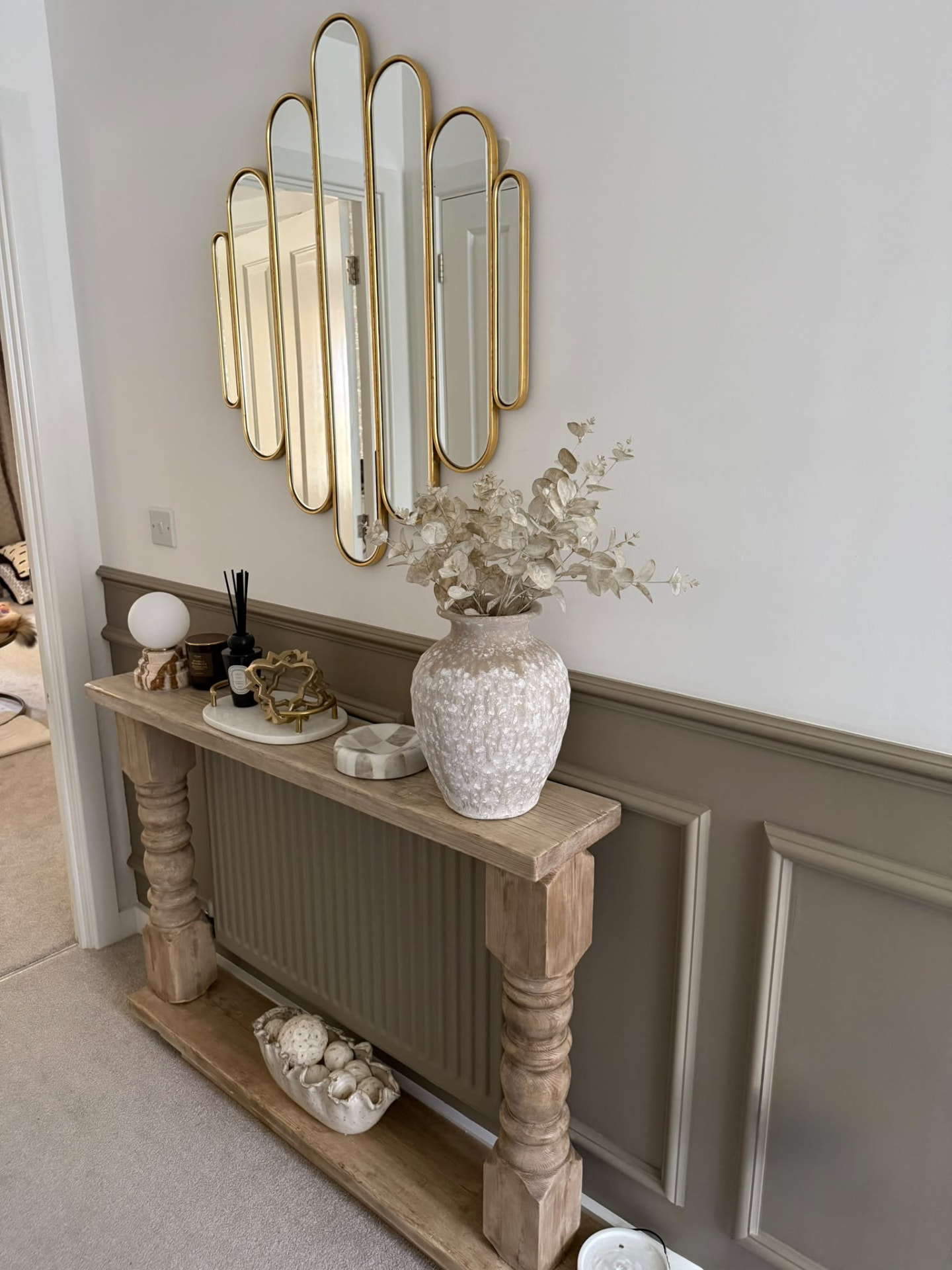 Finished entryway with wall panelling, console table and sculptural mirror